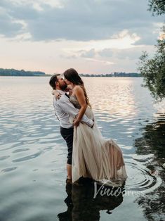 a bride and groom kissing in the water at their lake wedding venue near edmonton, canada