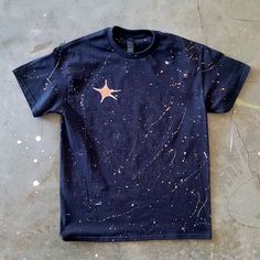 a blue t - shirt with stars on it is laying on the ground next to a pair of scissors