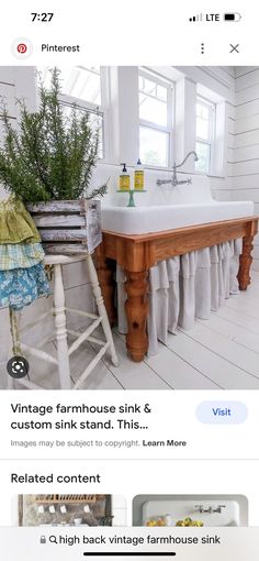 a white sink sitting under a window next to a wooden chair and potted plant