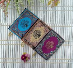 three different colored books sitting next to each other on top of a white tablecloth