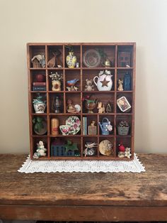 an old wooden shelf filled with figurines on top of a table