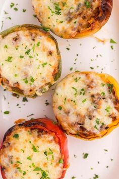 three stuffed peppers on a white plate with parsley