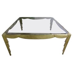 a glass and brass coffee table with two legs on the bottom, one leg raised up to