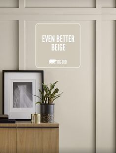 a white sign that says even better beige next to a potted plant on a dresser