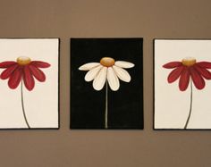 three red and white flower paintings hanging on a wall