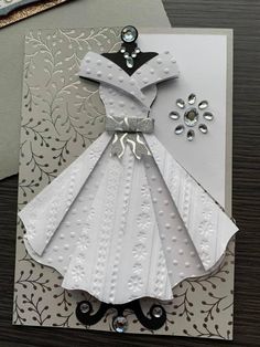 a handmade card with a dress on the front, and an embellishment in the back