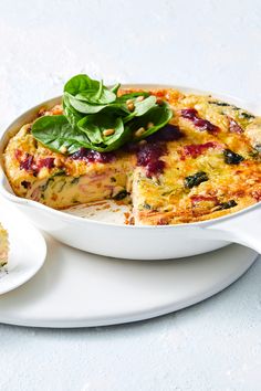 a white plate topped with a casserole covered in cheese and spinach next to a slice of bread