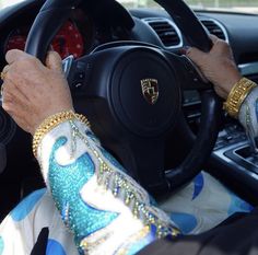 an older woman driving a car with her hands on the steering wheel and wearing gold bracelets