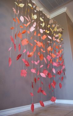 a wind chime with red and yellow leaves hanging from it's sides in a room