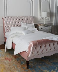 a white bed with pink velvet headboard and foot board, in a bedroom setting