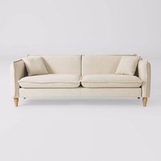 a cream colored couch with two pillows on it's arms and backrests