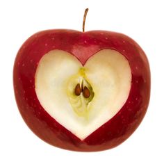 an apple with a heart shaped cut in half on top of it's side