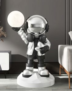 an astronaut statue is standing in the middle of a living room with grey walls and white furniture