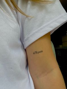 a woman with a small tattoo on her arm that says 11 11 pass in cursive writing