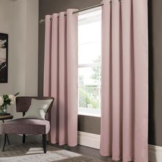 a living room with pink curtains and a chair in front of a window that has a painting on the wall