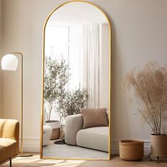 a living room with a couch, chair and large gold mirror in it's corner