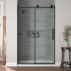 a bathroom with a glass shower door next to a small table and potted plant