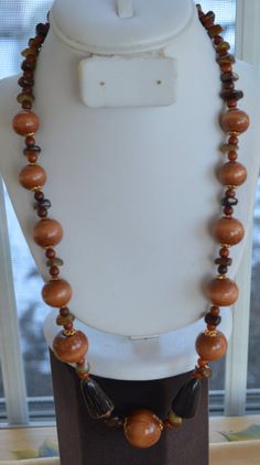 "Featuring this very attractiveshades of brown beaded necklace that is a mix of wooden, stone and horn beads. The wooden beads have gold tone filigree cap accents. The necklace measures 26\" in length and has a spring ring clasp. The necklace is in very good vintage condition." Brown Beaded Necklace, Orange Agate, Horn Necklace, Purple Rhinestone, Love Blue, Bib Necklace, Rhinestone Necklace, Wooden Beads, Spring Rings