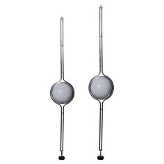 two metal spoons with white balls on them are standing side - by - side