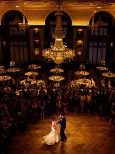 a bride and groom sharing their first dance in front of an audience at the reception