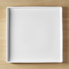 an empty white plate on a wooden table