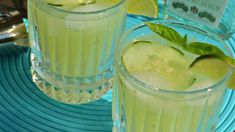 two glasses filled with cucumber and limeade on top of a blue plate