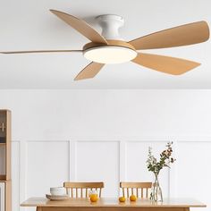 a white ceiling fan sitting above a dining room table with fruit and flowers on it