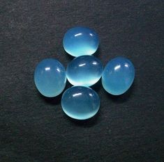 four blue glass balls sitting on top of a black table next to a cell phone