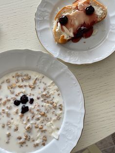 two white plates with food on them sitting on a table next to another plate that has cereal and yogurt in it