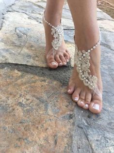 a woman's feet wearing barefoot sandals and beaded ankle bracelets on top of a rock