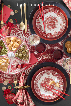 the table is set with red and white plates, utensils, and silverware