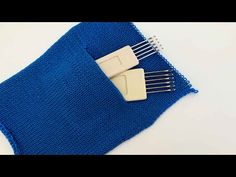 a blue knitted cloth with two plastic combs sticking out of it