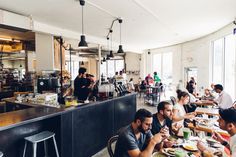 people sitting at tables in a restaurant eating food and drinking beverages on the sidelines