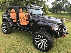 a black jeep with tan leather seats parked in the grass