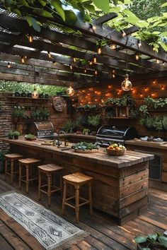 an outdoor kitchen with lots of seating and lights on the ceiling, surrounded by greenery