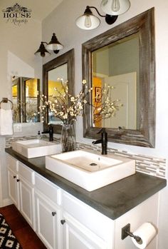 a bathroom with two sinks, mirrors and lights on the wall above them is shown