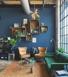 a living room filled with furniture and lots of windows next to a brick wall covered in plants