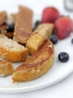 a white plate topped with different types of breads and berries on top of it