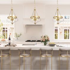 a white kitchen with gold bar stools next to the island and countertop area