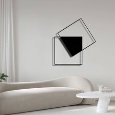 a modern living room with white furniture and black artwork on the wall, along with a round coffee table