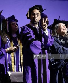 a group of people in graduation gowns and hats standing together with one man giving the peace sign