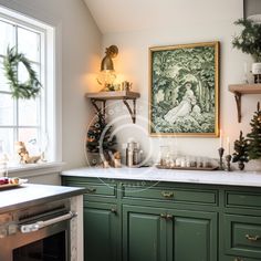 a kitchen decorated for christmas with green cabinets and white counter tops, an art piece on the wall