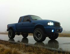 a blue pick up truck driving down a wet road