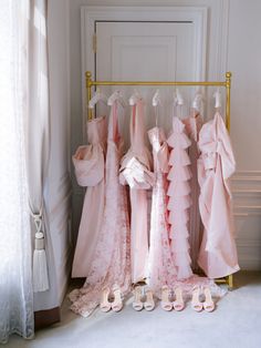 pink dresses and shoes are lined up on a rack