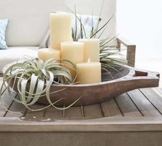 a wooden tray with candles and air plants on it