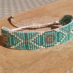 a close up of a beaded bracelet on a wooden table with beads around it