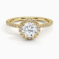 a yellow gold engagement ring with an oval cut diamond surrounded by small round brilliant diamonds