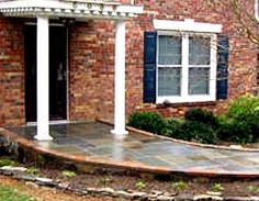 a brick house with blue shutters on the front and side windows, along with a stone walkway leading up to it