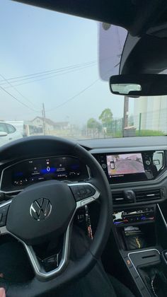 the interior of a car with dashboard, steering wheel and display screen showing various vehicles