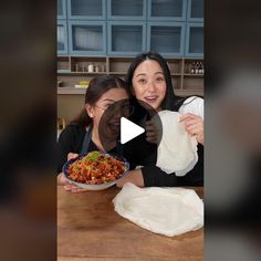 two women pose for a video while holding food in front of their face and making funny faces